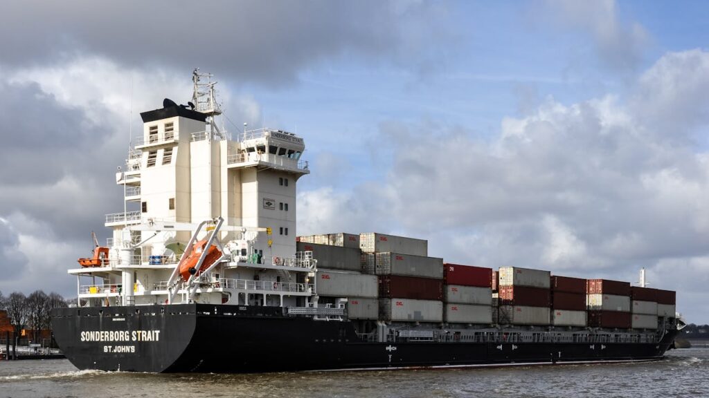 pexels photo 30012661 Container ship navigating Hamburg harbor with stacked cargo under a cloudy sky.